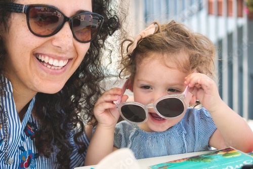 A mother a daughter wearing dark sunglasses, smiling and laughing and having fun