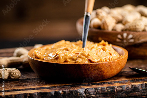 Peanut butter and inshell peanuts on a cutting board. 