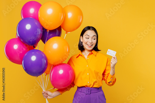 Happy fun surprised smiling amazed young woman wears casual clothes celebrating hold balloons use mobile cell phone look camera isolated on plain yellow background Birthday 8 14 holiday party concept © ViDi Studio