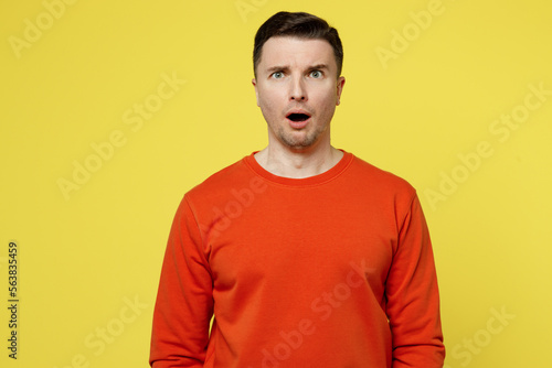 Young shocked sad astonished disturbed caucasian man wearing orange casual clothes looking camera with opened mouth isolated on plain yellow color background studio portrait. People lifestyle concept.