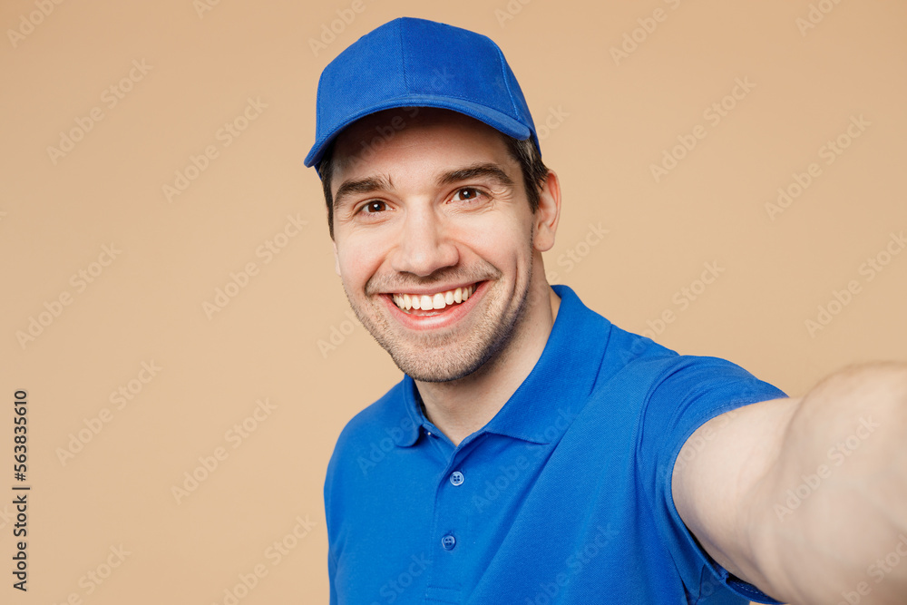 Close up delivery guy employee man wear blue cap t-shirt uniform workwear work as dealer courier doing selfie shot pov on mobile cell phone isolated on plain light beige background. Service concept. Close up delivery guy employee man wear blue cap t-shirt uniform workwear work as dealer courier doing selfie shot pov on mobile cell phone isolated on plain light beige background. Service concept.