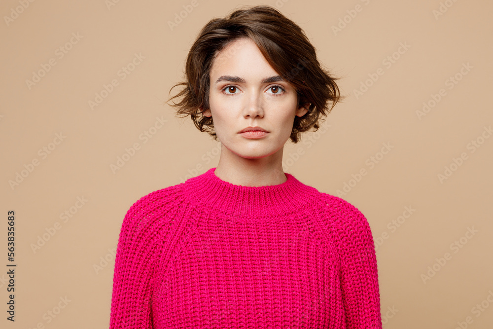 © ViDi Studio - Young brunette european calm serious attractive beautiful caucasian woman wearing pink sweater looking camera isolated on plain pastel light beige background studio portrait. People lifestyle concept.