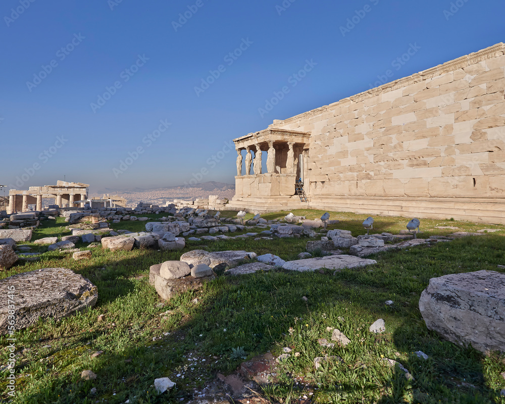 Unusual view of the famous Erechtheion ancient Greek temple with partial view of Caryatids, under crystal clear blue sky. Acropolis of Athens, Greece.
