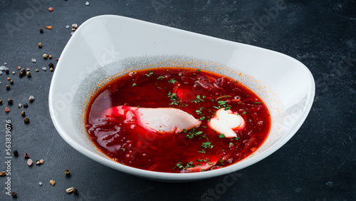 Russian red borscht soup made from beets, potatoes, cabbage, onions and spices with sour cream and greens.