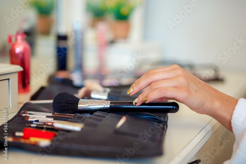 Selective focus, woman's hand picking makeup brush. Makeup at home