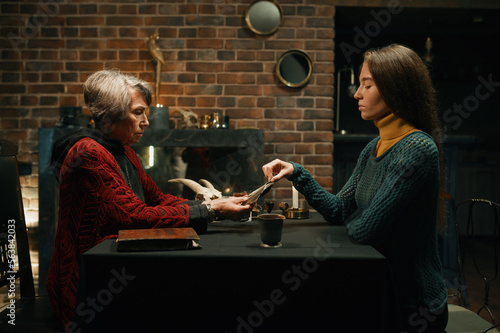 Canvas Print Old mature soothsayer holding divination tarot cards in front of client