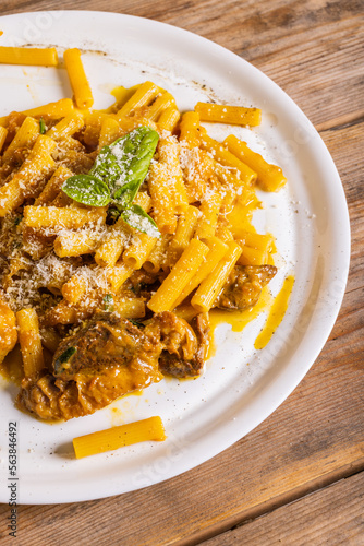 Piatto di pasta con sugo di genovese napoletana con carne e cipolle guarnito con formaggio grattugiato e basilico fresco servito in un ristorante napoletano photo