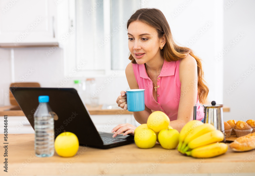 Woman cook reads the recipe in laptop and cooks salad in kitchen Woman cook reads the recipe in laptop and cooks salad in kitchen