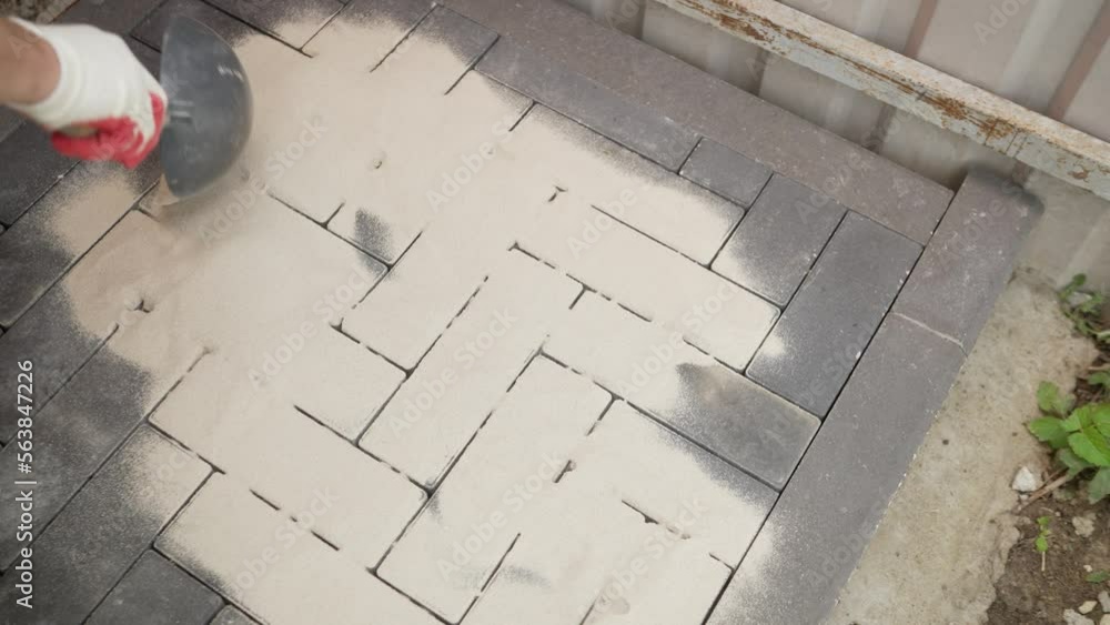 The worker fills the seams in the paving slabs. The final step in