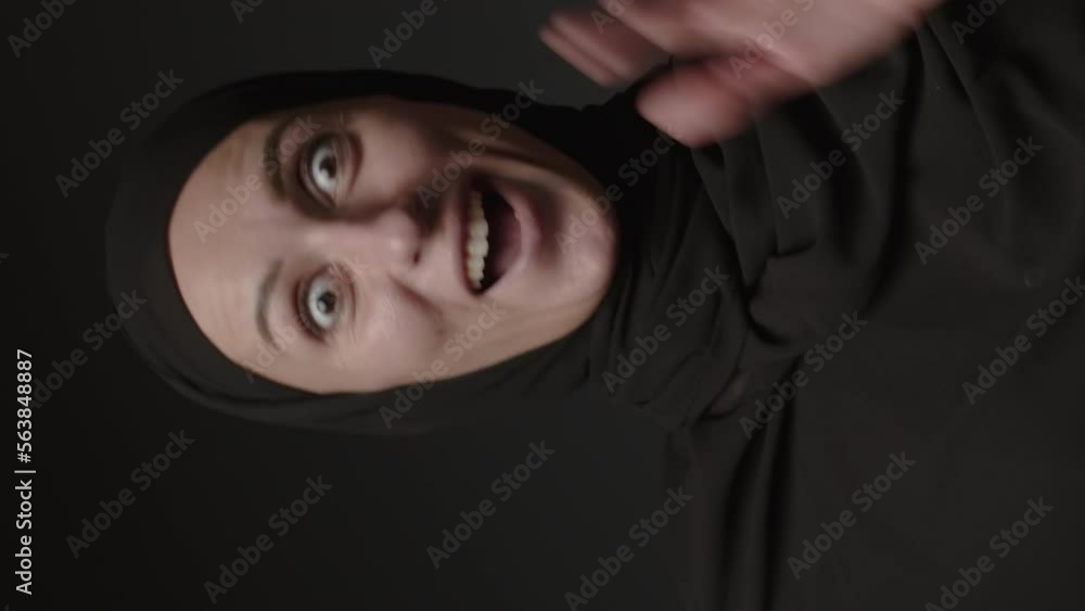 Vertical video of surprised excited female in hijab shocked with unbelievable offer isolated on black background. Amazed woman. Wow face Vertical video of surprised excited female in hijab shocked with unbelievable offer isolated on black background. Amazed woman. Wow face