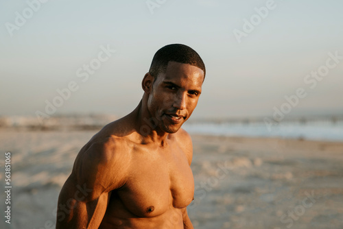 Smiling man standing on beach at sunset photo