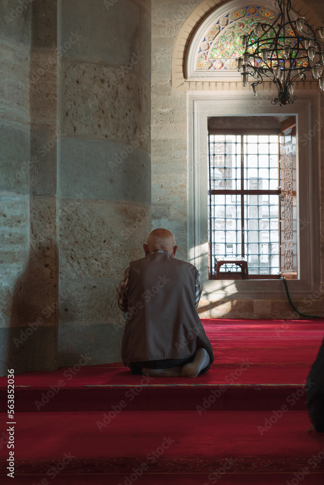 Islamic vertical photo. An elder muslim man praying in the mosque.