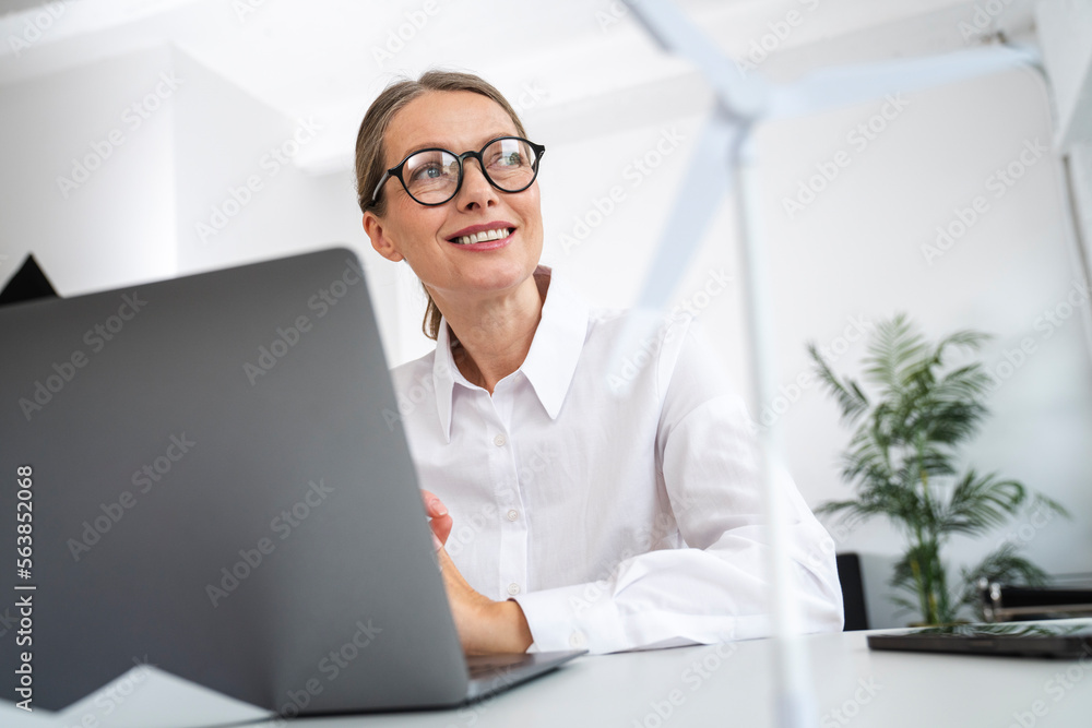 Thoughtful mature businessman sitting in front of laptop at desk in office Thoughtful mature businessman sitting in front of laptop at desk in office
