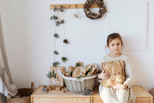 Smiling girl holding gift box from homemade advent calendar at home photo