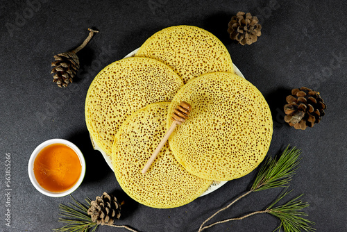 Moroccan or Algerian pancakes named Baghrir in arabic with honey syrup bowl and  and dry mint, pine cones photo