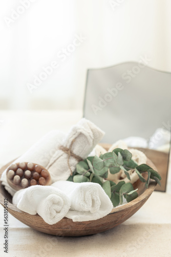 Spa composition with soap, bath bomb and towels in a wooden bowl.