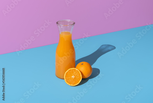 Orange juice carafe and orange fruits isolated on a vibrant background