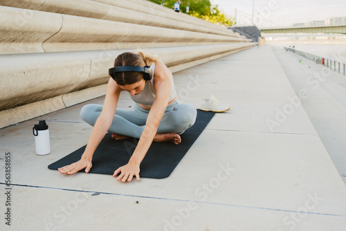 Young woman doing sport stretching exercises outdoors photo