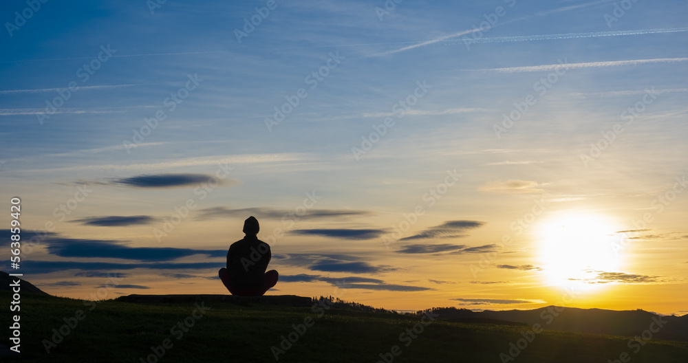 Man in yoga pose, zen meditation at sunset.