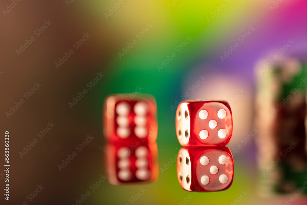 Casino theme. Gambling games. Dices and poker chips on a colorful bokeh background. Casino theme. Gambling games. Dices and poker chips on a colorful bokeh background.