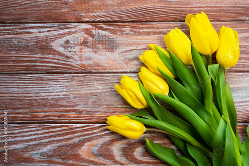 Flatlay composition with bouquet of yellow tulips on a wooden background. Top view. Place for text. Selective focus.
