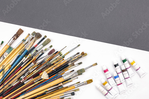 Brushes for drawing and paint on paper colored background, flat lay.