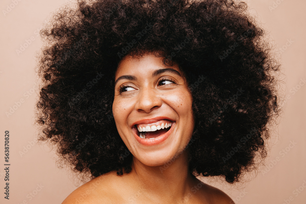 Gorgeous woman with an Afro hairstyle smiling happily in a studio Gorgeous woman with an Afro hairstyle smiling happily in a studio