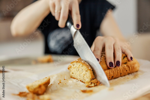 Close up of a hand cutting healthy bread at home.