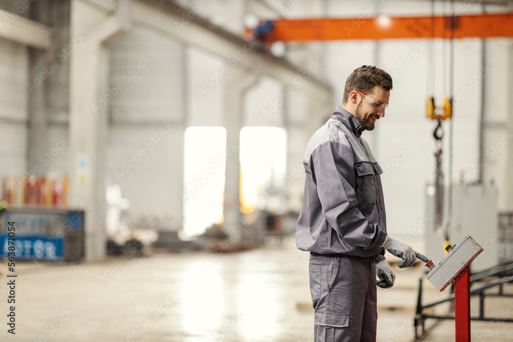 Profile of a heavy industry worker pressing a button on a machine.