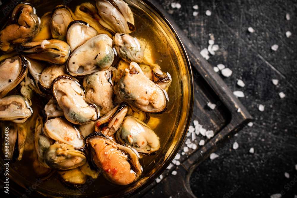 Bowl with pickled mussels on a cutting board. Top view. Bowl with pickled mussels on a cutting board. Top view.