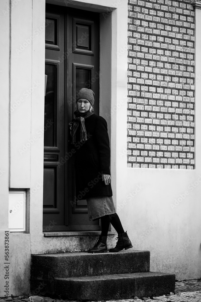 A sad woman on the porch of the house knocks on the door. Black and white photo. A sad woman on the porch of the house knocks on the door. Black and white photo.