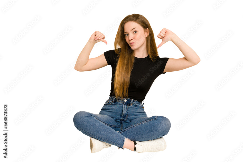 Young redhead woman sitting on the floor cut out isolated feels proud and self confident, example to follow. Young redhead woman sitting on the floor cut out isolated feels proud and self confident, example to follow.