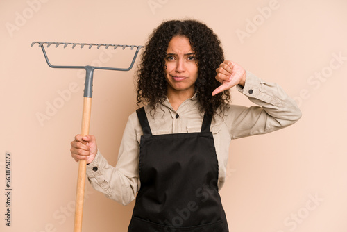 Quadro su tela Young african american gardener woman holding a rake isolated showing a dislike gesture, thumbs down
