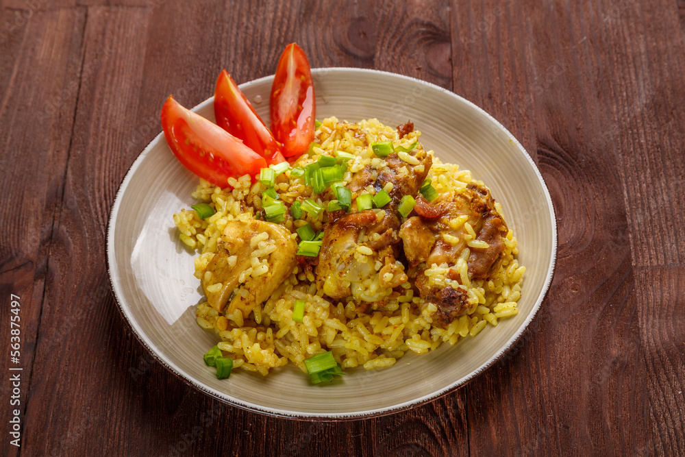 Rice chicken in teriyaki sauce garnished with green onions on a wooden table. Rice chicken in teriyaki sauce garnished with green onions on a wooden table.