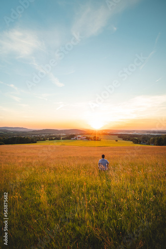 Man sitting in a cornfield thinks about his future looking into the sunset. Self-education, mastering mindfulness. Beskydy mountains, Czech Republic