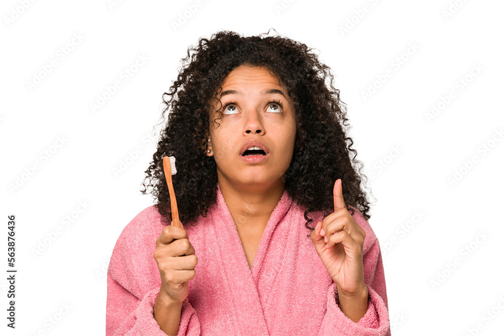 Young african american curly woman after shower toothbrushing isolated pointing upside with opened mouth. Young african american curly woman after shower toothbrushing isolated pointing upside with opened mouth.