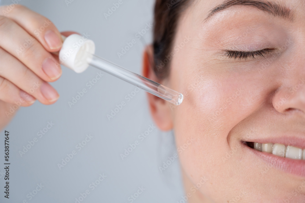 Caucasian woman uses blue anti-wrinkle face serum. Caucasian woman uses blue anti-wrinkle face serum.