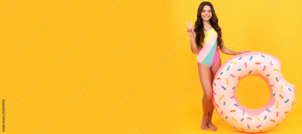 Summer child. kid in swimming suit with doughnut inflatable ring on yellow background, summer vacation. Banner of summer child girl in swimsuit, studio poster header with copy space.