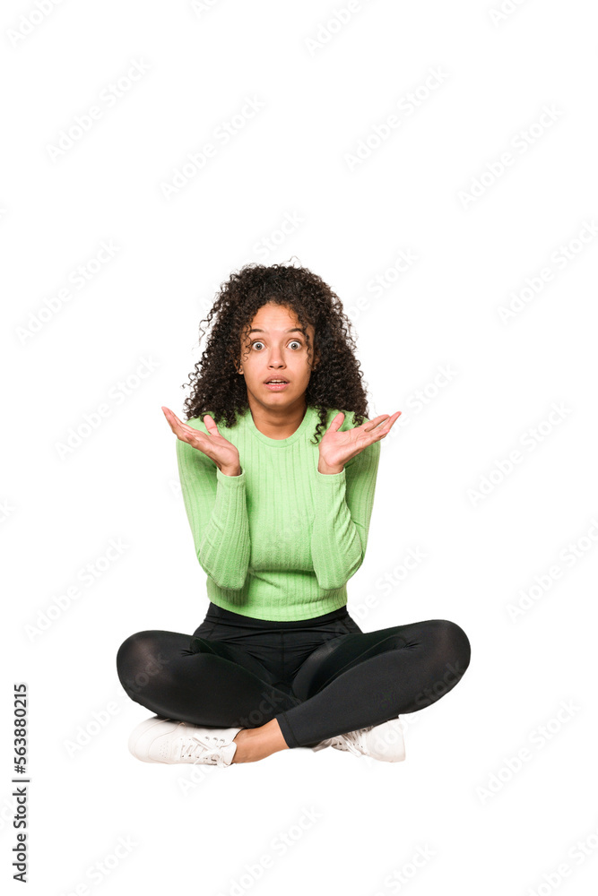 Young african american curly woman sitting on the floor isolated Young african american curly woman sitting on the floor isolated