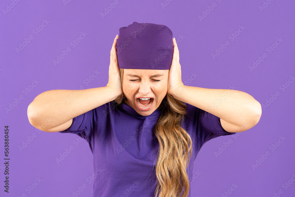 Despaired young angry woman shouting while covering ears isolated on purple background. Feminism, gender violence and equality concept Despaired young angry woman shouting while covering ears isolated on purple background. Feminism, gender violence and equality concept