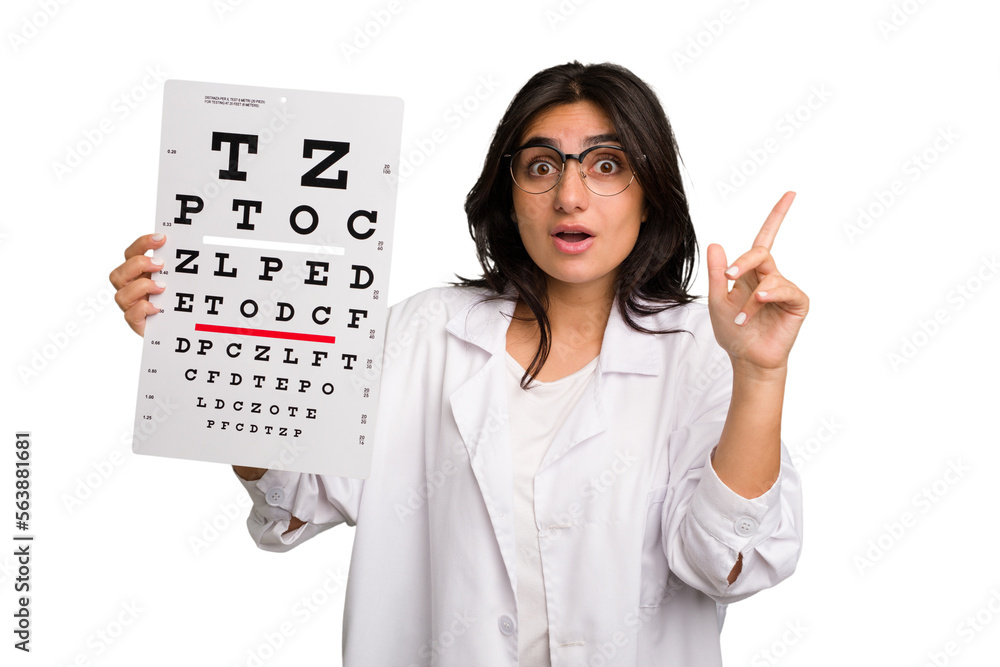 Young indian oculist woman holding an eye chart paper cut out isolated having an idea, inspiration concept. Young indian oculist woman holding an eye chart paper cut out isolated having an idea, inspiration concept.