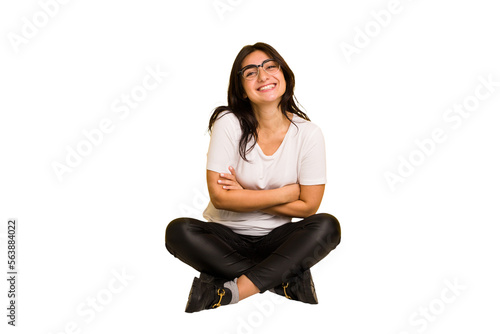 Young indian woman sitting on the floor cut out isolated laughing and having fun.