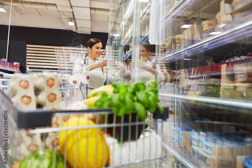 Frau beim Einkaufen im Supermarkt mit Einkaufswagen photo