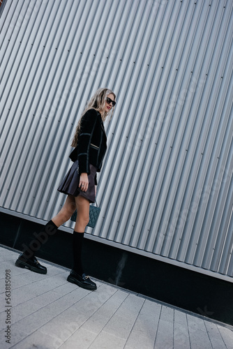glamorous lady with long legs in a black jacket walking on the street