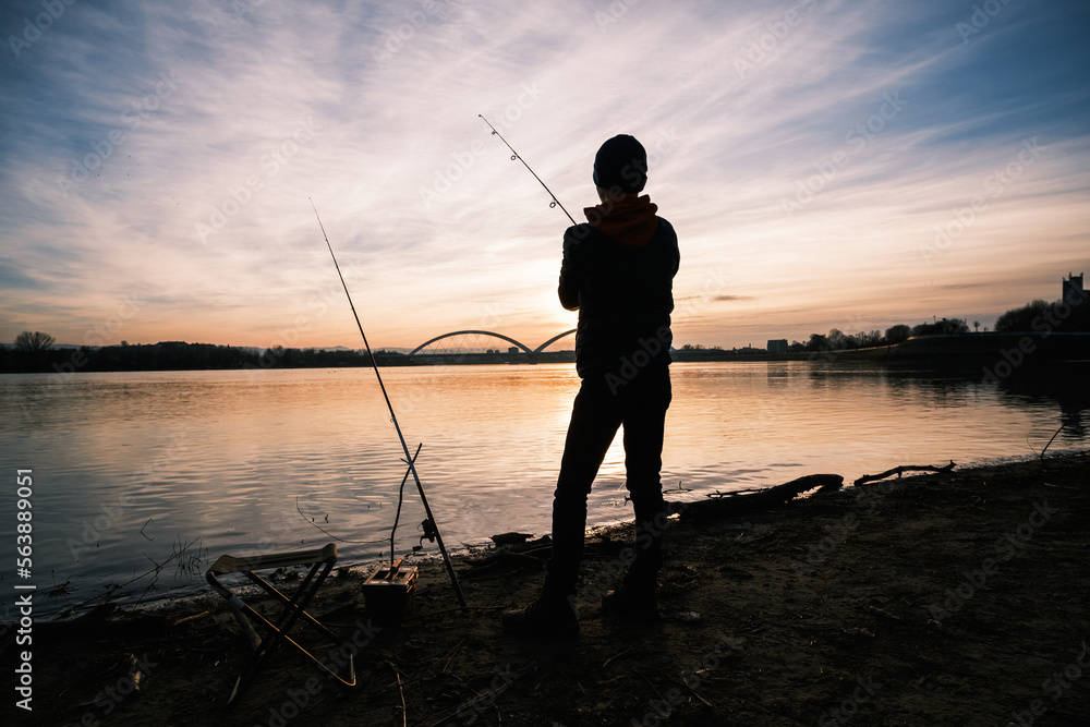 Teenage boy is fishing on river bank. Boy is fishing in sunset. Teenage boy is fishing on river bank. Boy is fishing in sunset.