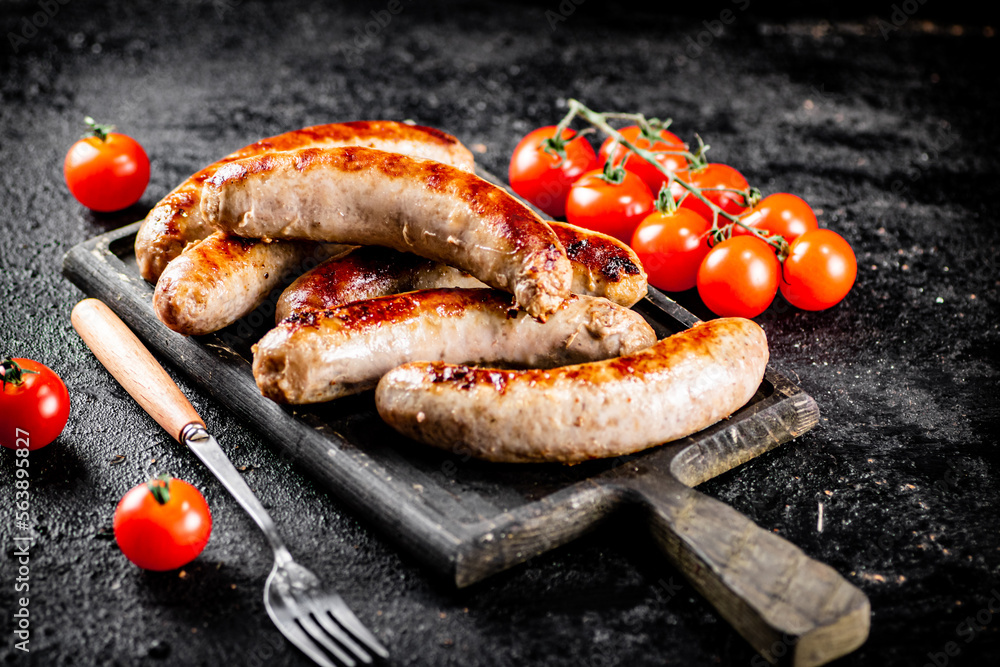 Grilled sausages on a cutting board with tomatoes. Grilled sausages on a cutting board with tomatoes.