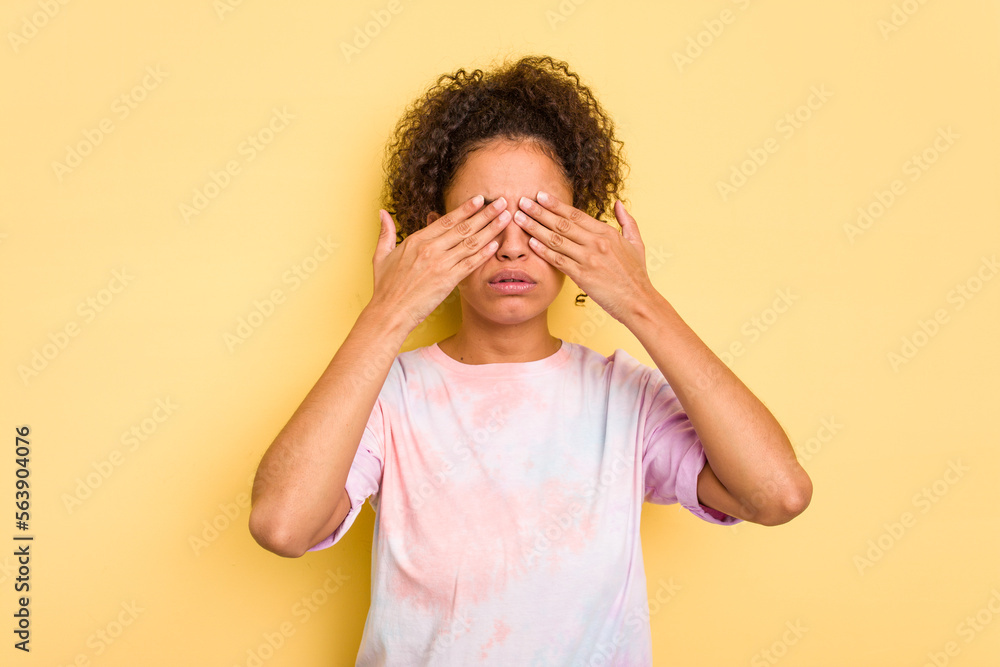 Young Brazilian curly hair cute woman isolated on yellow background afraid covering eyes with hands. Young Brazilian curly hair cute woman isolated on yellow background afraid covering eyes with hands.