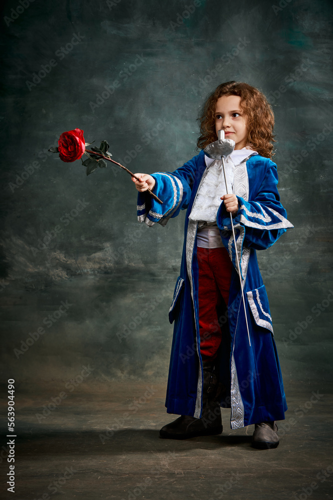 Fototapeta premium Emotional kid, little girl wearing costume of prince, musketeer and royal person posing over dark vintage style background. Fashion, theater, beauty, emotions concept