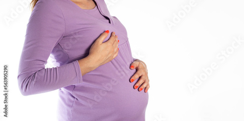 A pregnant girl in a purple blouse holds her chest. The concept of pain and changes in the female breast in pregnant women due to hormonal levels. Copy space for text photo