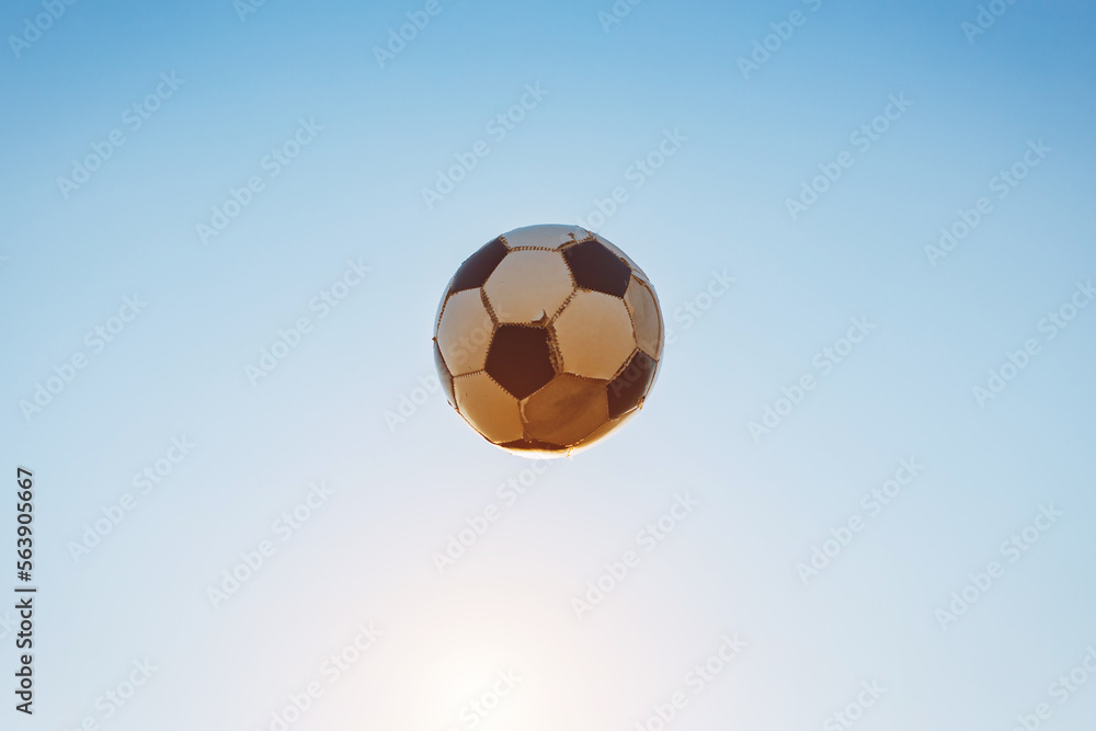 Fototapeta premium Low angle view of classic black and white ball or soccer football flying in twiligth sky. Sport game and athlete concept with no people.